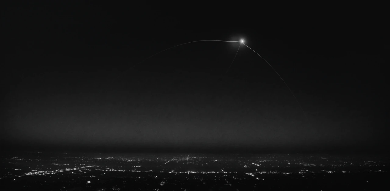 Faint arcs of light meet in a small white burst high above a sleeping city at night.